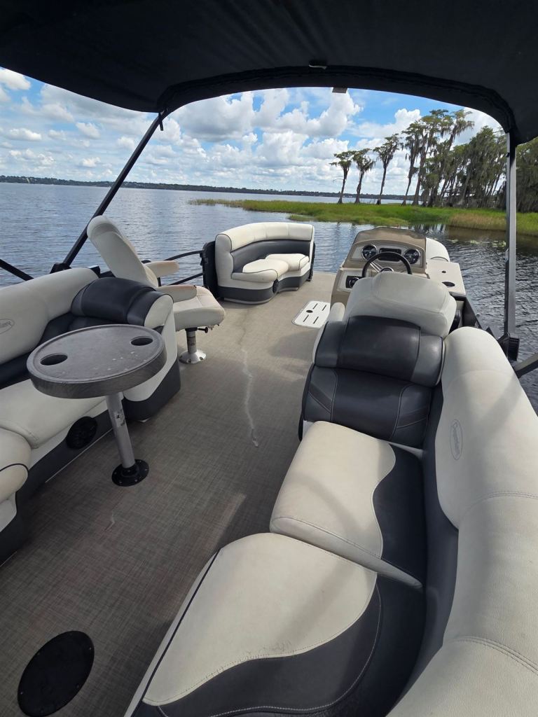 Name That Toon's open deck with table, lounge seating and helm, looking out over the lake
